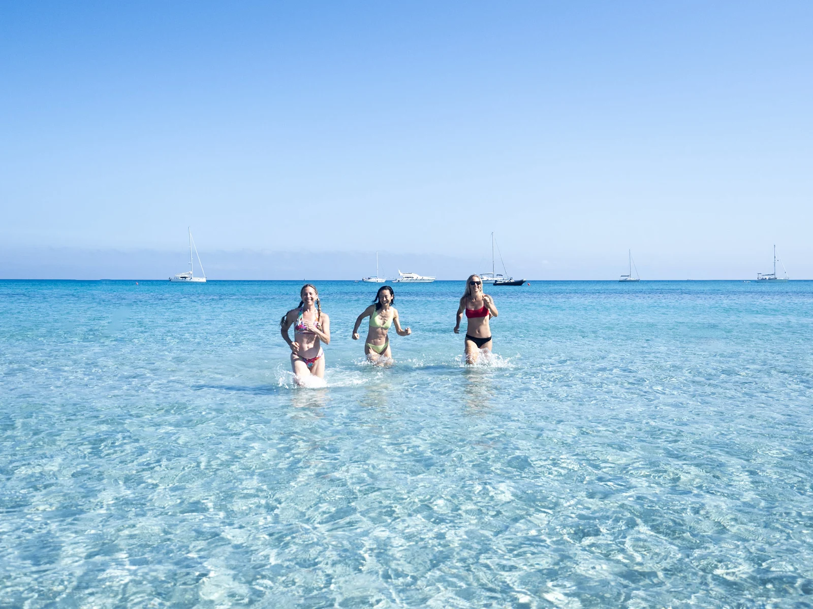 Fun running in sea water, with sail boats behind.